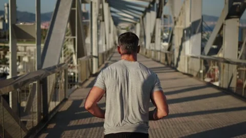 Follow back unrecognizable mature strong man running alone on urban bridge Stock Footage 264768615