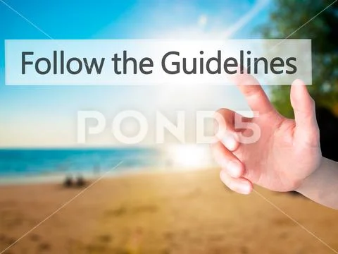 Follow the Guidelines - Hand pressing a button on blurred backgr Stock Photos