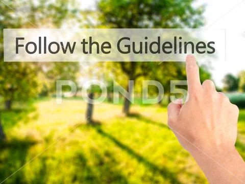 Follow the Guidelines - Hand pressing a button on blurred backgr Stock Photos