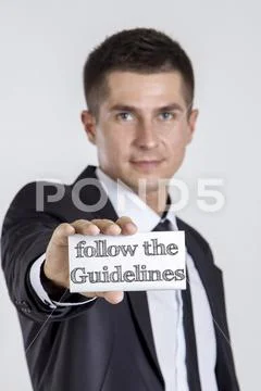 Follow the Guidelines - Young businessman holding a white card with text Stock Photos