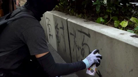 Follow Shot of a man spray painting during a protest in Hongkong Stock Footage