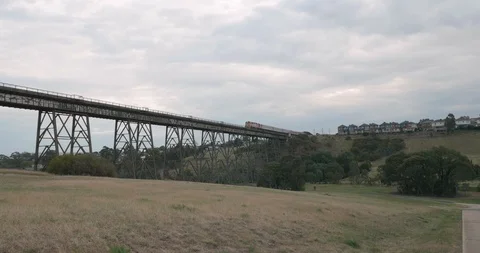 Follow view of a train crossing a old historic narrow trestle railway bridge Video stock 117339488