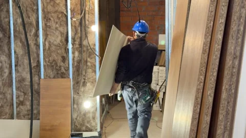 Following a construction worker with a tool belt at a building site Vídeos de archivo 336238390