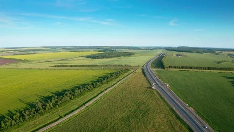 Following the highway between green fields and trees. 스톡 동영상 111384098