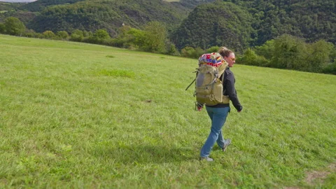 Following hiking backpacker walking down a hilly green grass meadow landscape Stock-Footage 303674597