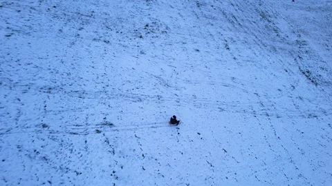 Following a man sledding down a snowy hill at sunset, Uster, Switzerland Stock Footage 322730714