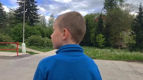 Following a school boy walking on the pathway surrounded by high trees. Stock Footage 116232428