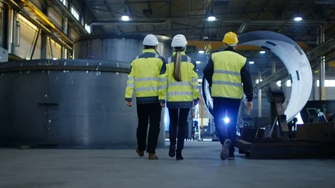 Following Shot of Three Engineers Walking Through Heavy Industry Factory Stock Footage