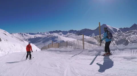 Following skiers skiing at speed down piste POV stabilized, snow blue sky Stock Footage 62522405