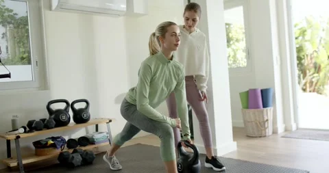 Following trainer cue, client stepping into kettlebell lunge at home gym on Stock Footage 344253731