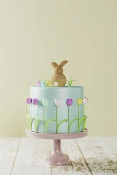 Fondant Easter cake with tulips, a bunny and Easter grass on pink cake stand, 3D Stock Illustration
