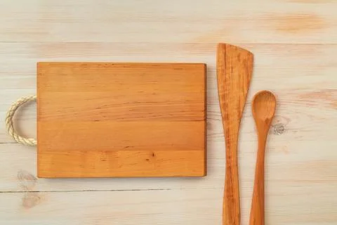Food background. Top view of empty wooden cutting board, spoon and spatula on Stock Photos
