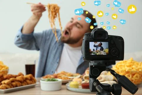 Food blogger recording eating show against light background, focus on camera  Stock Photos
