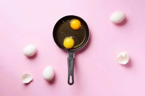 Food concept with two eggs, shells, pan on pink background. Top view. Creative Stock Photos