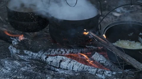Food is cooked in three black pots at the stake. Stock Footage 130445300
