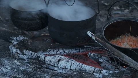 Food is cooked in three black pots at the stake. Stock Footage 130445382