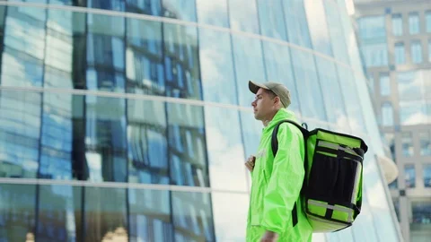 Food courier with backpcj walking down street Stock Footage 113992409