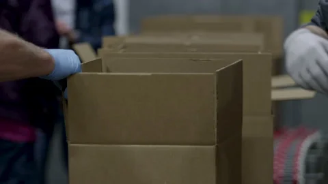 Food donation boxes going down a line of gloved volunteers 스톡 동영상 130996748