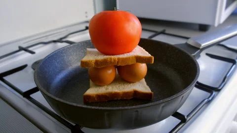 Food installation with two eggs between bread slices and tomato in skillet. Stock Footage 318213782