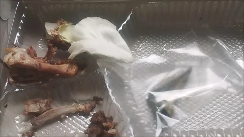 Food Leftovers with Chicken Bones, Cabbage Leaf, Plastic Wrapper, and Tissue Stock Footage 296850751