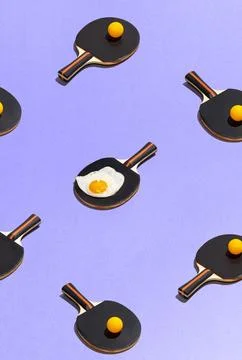 Food pattern with fried egg on table tennis racket on purple background flat lay Stock Photos