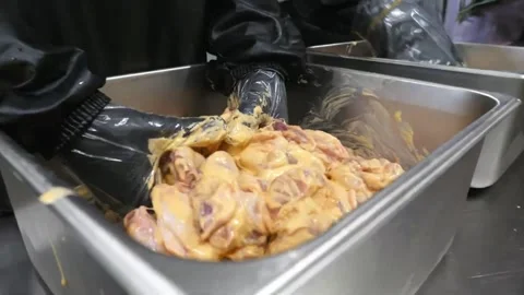Food prep worker wearing black gloves marinating raw Korean fried chicken in a m Video stock 343028770
