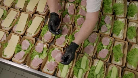 Food preparation process showing a gloved hand placing slices of ham on Stock Footage 340172452