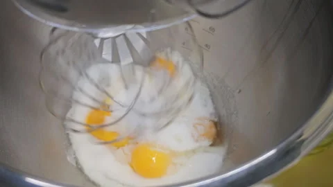 Food processor beat egg yolks, eggs and sugar in a metal bowl using an electric Stock Footage 275590058
