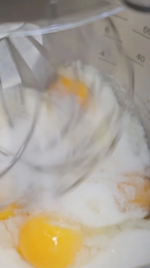 Food processor beat egg yolks, eggs and sugar in a metal bowl using an electric Stock Footage 275686336