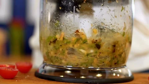Food processor blends basil leaves and walnuts for pesto Stock Footage 333875812