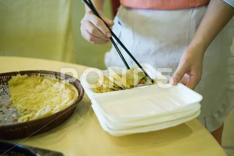 Food Service Personnel Using Chopsticks To Place Food In Polystyrene Container