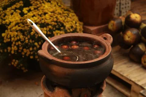 Food simmering in a rustic earthenware pot over a charcoal fire in Vietnam Stock Photos