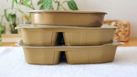 Food storage containers stacked on a table with plants in the background Stock Footage 346339951