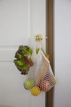 Food in a string bag on a white background. The concept of green shopping. Stock Photos