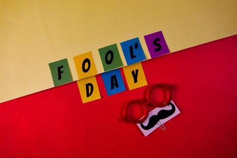 Fools day text on red and yellow background top view Stock Photos