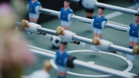 Foosball, kicker, blue and white toy soccer players pass the ball to each other Stock Footage 129075291