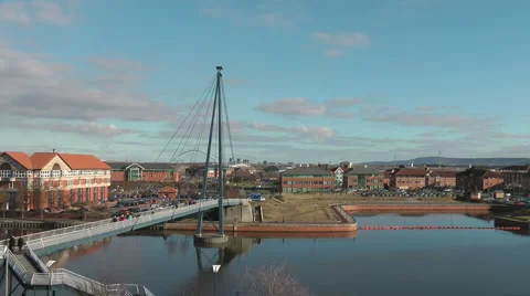 Foot bridge over urban river with modern office blocks, workers cross bridge Stock Footage 1079669