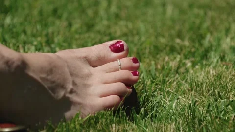 Foot with Red Painted Toenails and Toe Ring Resting on Green Grass Video stock 336037367