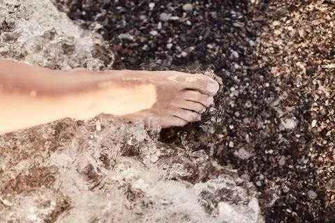 Foot in Refreshing Waves on Pebble Beach with Natural Sunlight Stock Photos