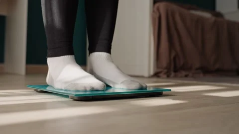 Foot on scale under warm sunlight showcases progress. Walking barefoot on glass Stock Footage 342421962
