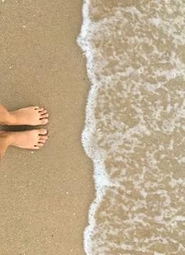 Foot stand on sea sand and wait wave coming, top down view Stock Photos