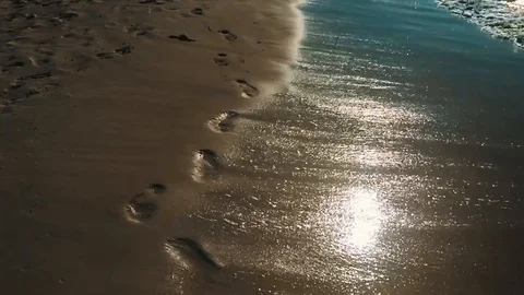 Foot Steps on the sand cover by blue sea waves Stock Footage