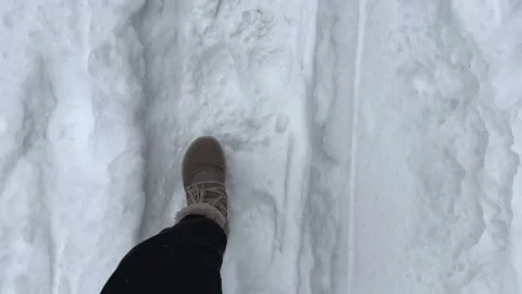A foot steps through soft, untouched snow, creating a visible path while Видео 334213852