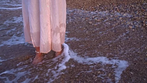 Foot steps in water on a beach wearing a long dress during sunset Stock Footage 342787529