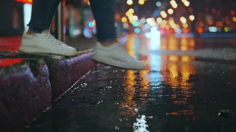 The foot of an unrecognizable person steps into a puddle, breezes fly Stock Footage 244494248