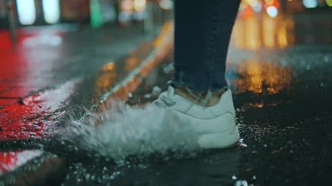 The foot of an unrecognizable person steps into a puddle, breezes fly Stock Footage 245187398