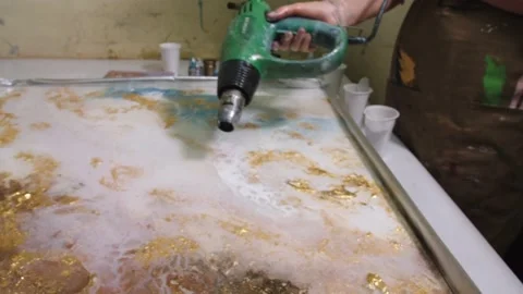 Footage of artist in protective gloves using electric hair dryer to spread Stock Footage 201389140