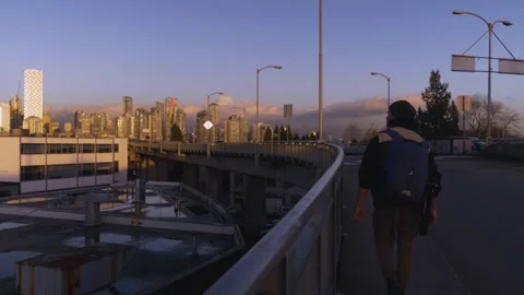 Footage the back of a Man walking along the sidewalk towards a bridge in Stock Footage 149105099
