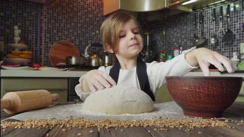Footage of a beautiful liithe 5 years old girl kneading the dough on the wooden Stock Footage 75803299