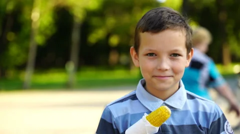 Footage boy eating boiled corn in a park close-up. 4k Video stock 64755366